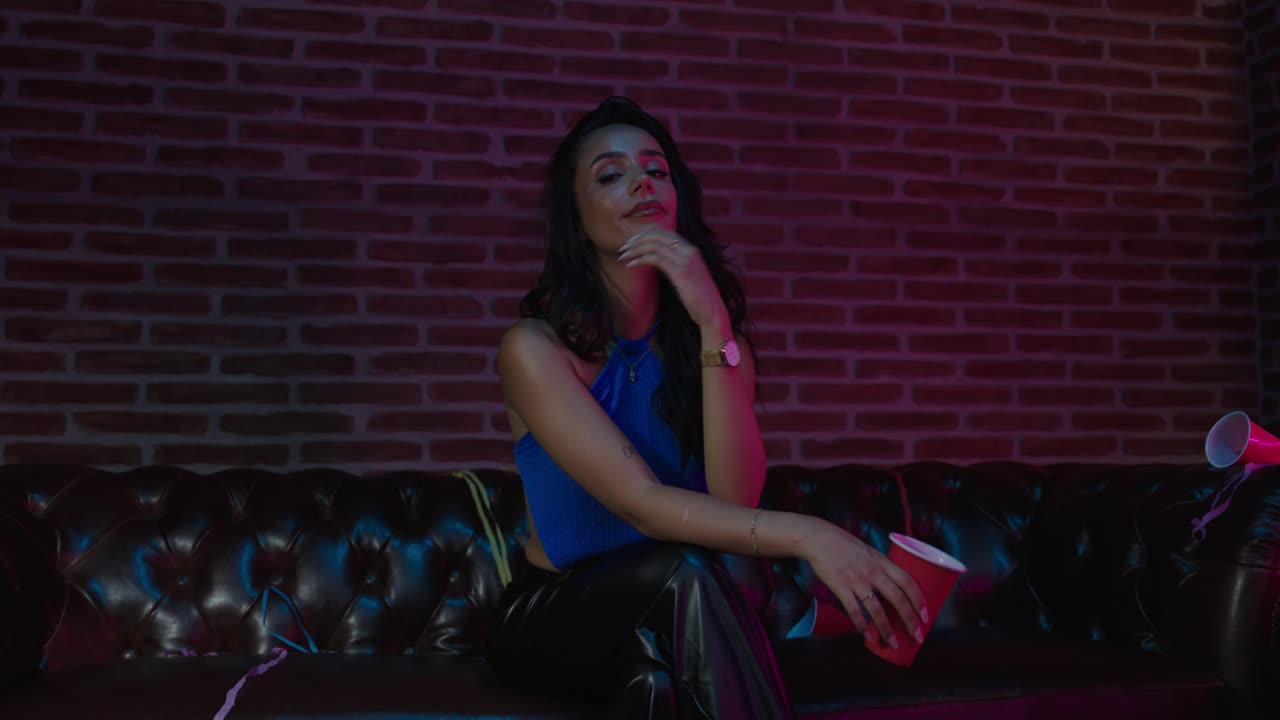 mujer sentada en el sofá durante una fiesta con una taza roja de 50p