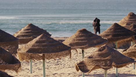 beach umbrellas or sunshades, people walking in background, copy space for titles