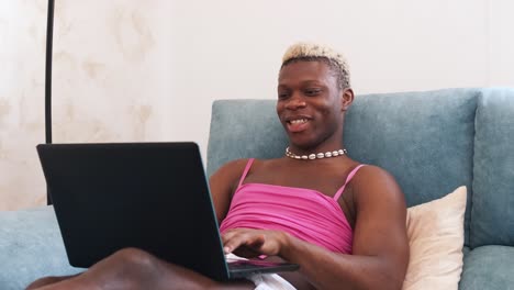 young african american person reacting while using a laptop on the couch