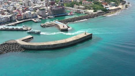 Spectacular-aerial-shot-of-a-ferry-boat-arriving-at-Baishawei-fishing-harbor-terminal-at-daytime-in-Xiaoliuqiu-Lambai-Island,-Pingtung-county,-Taiwan