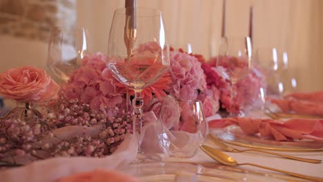 elegant wedding dinner table with pink flower decoration, golden cutlery, dolly