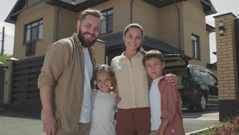 una feliz familia de cuatro personas posando delante de la casa