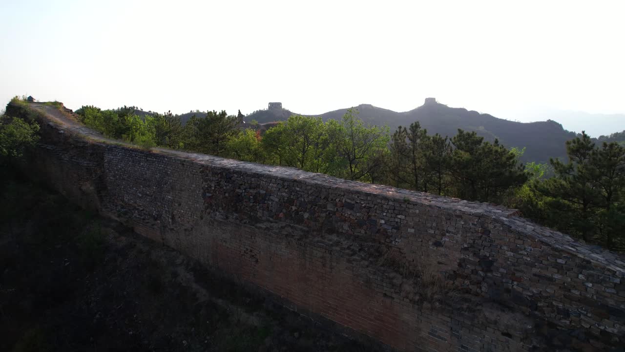 una pareja volando un dron sobre la sección no restaurada de gubeikou de la gran muralla china al atardecer