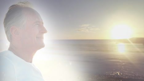 animation of glowing light over happy senior man by seaside