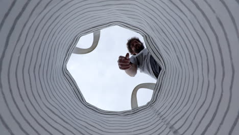 Low-angle-bearded-male-dropping-plastic-bottle-into-garbage-recycling-rubbish-bag