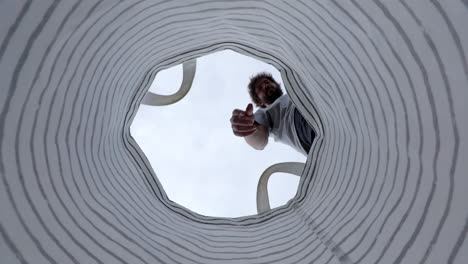 Low angle bearded male dropping plastic bottle into garbage recycling rubbish bag
