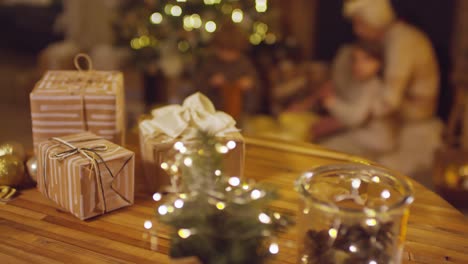 close up of christmas gifts on a table, grandmother playing with her grandchildren on the background