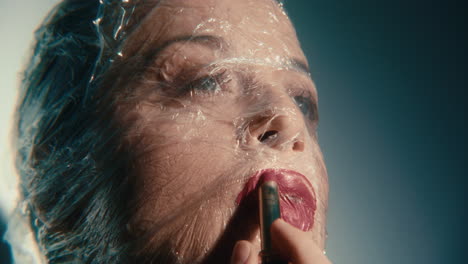 woman with plastic wrap on face getting makeup applied