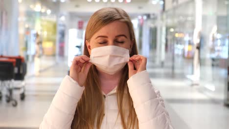 blonde woman putting on medical mask on crowdy street.