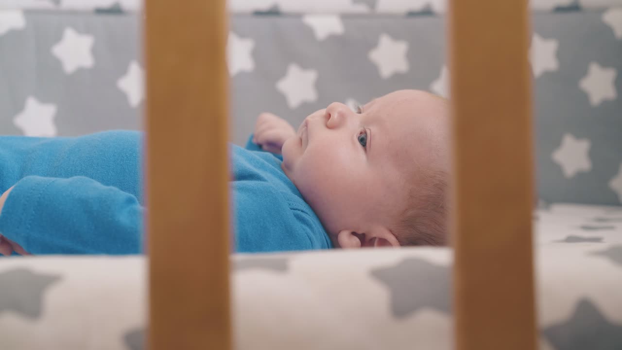 ragazzo neonato in bodysuit azzurro muove le mani riposando nella culla