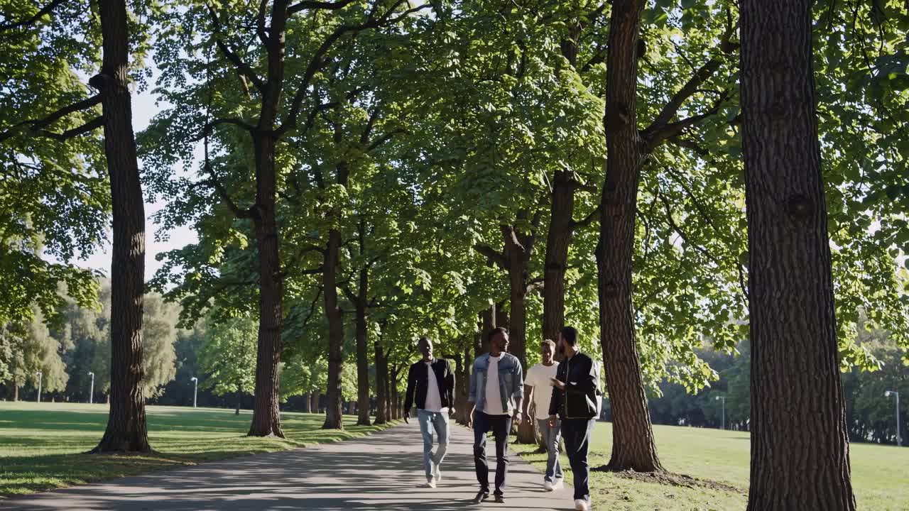 A group of friends walking through a sunlit park, captured from a low-angle, conveying a lively