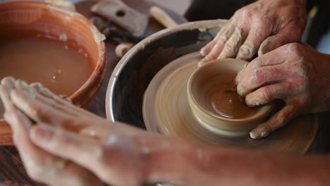 two guys use potter's wheel to create handmade clay product