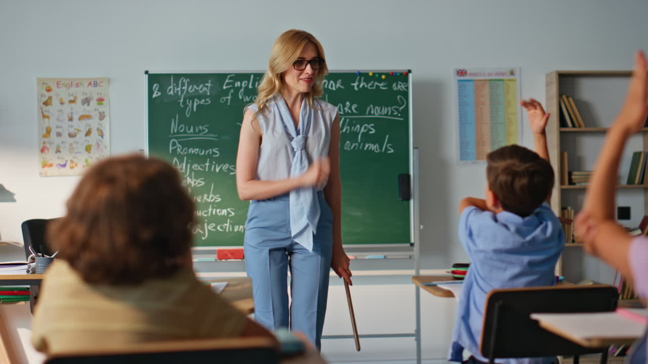 Woman interacting class children at english lesson. Smiling teacher asking