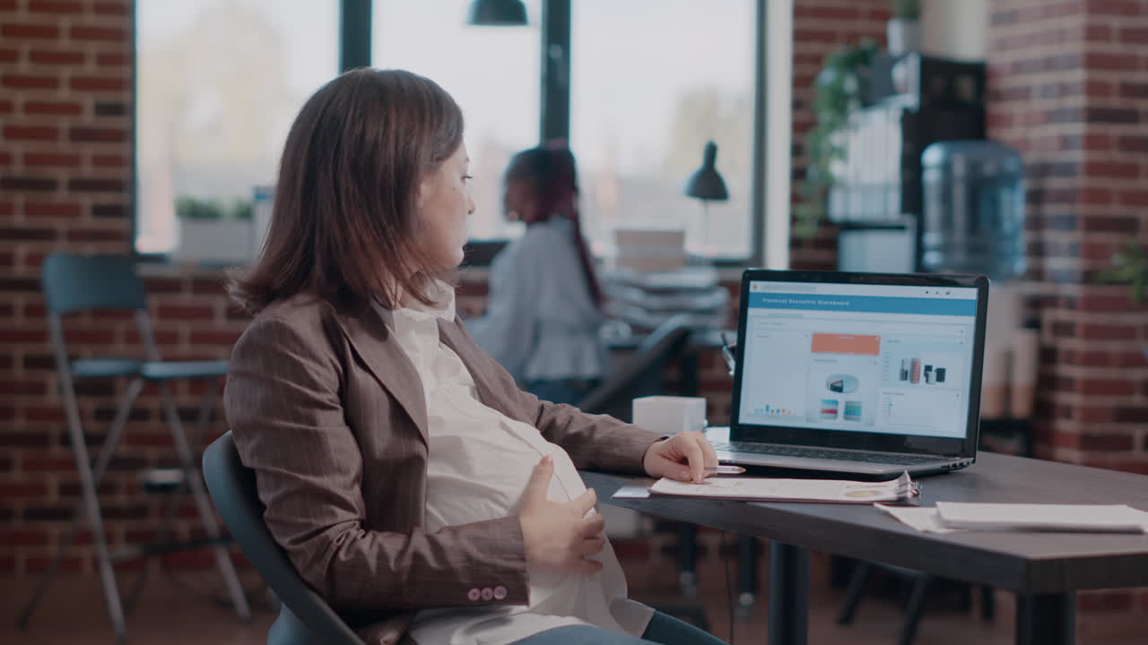 Close up of pregnant woman holding hand on belly working on business strategy