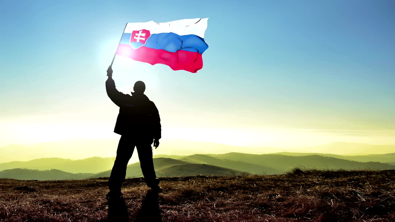успешный силуэт мужчины-победителя, размахивающего флагом словацкой республики на вершине горы, цинмографный цикл на заднем плане