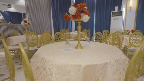 una sala de banquetes bellamente diseñada con sillas de oro de lujo y una mesa redonda con elegantes centros florales, creando un ambiente exquisito y sofisticado