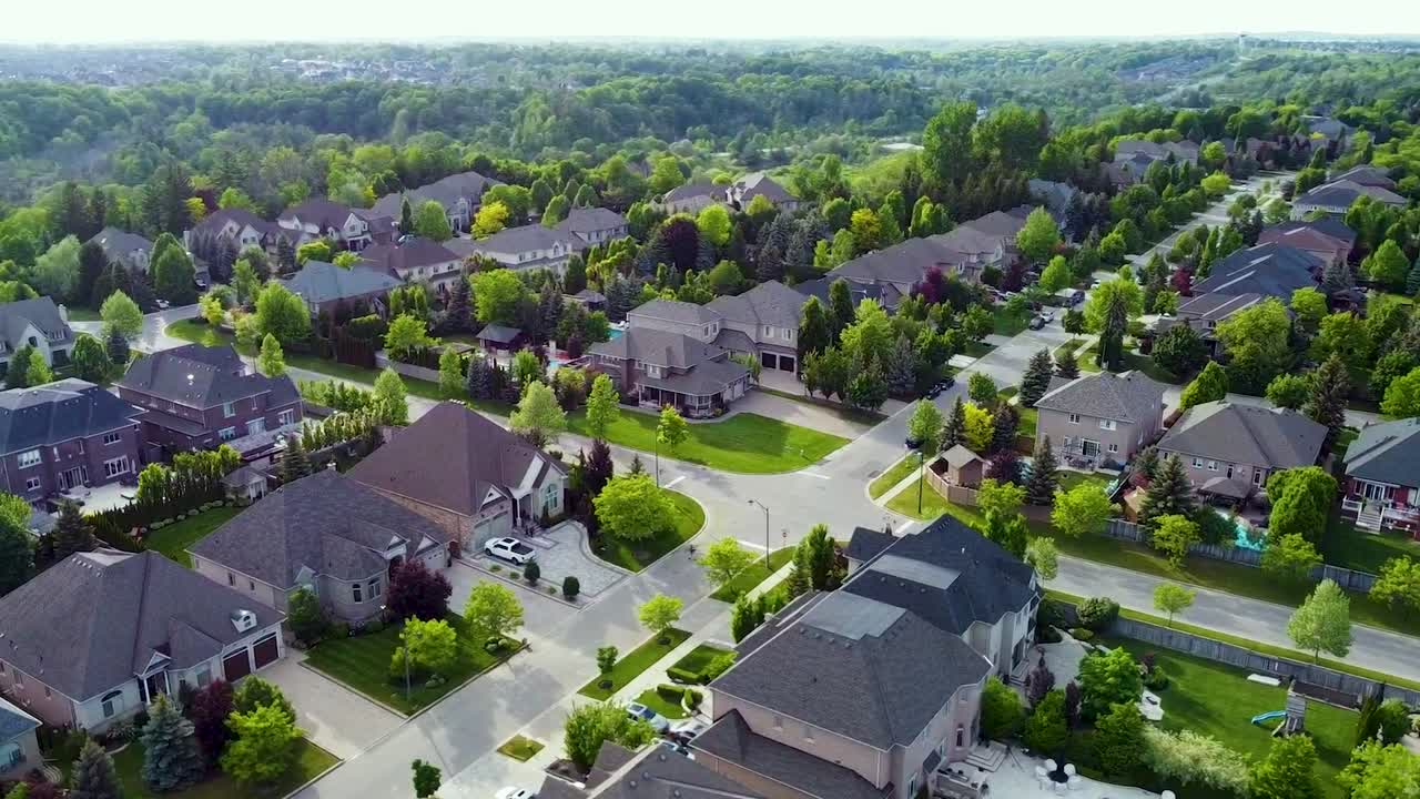 Sirkulerende droneopptak av et veikryss med solrike hus i Kleinburg