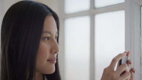 portrait-of-young-asian-woman-using-smartphone-taking-photo-enjoying-mobile-camera-photography-in-window-background-leisure-hobby