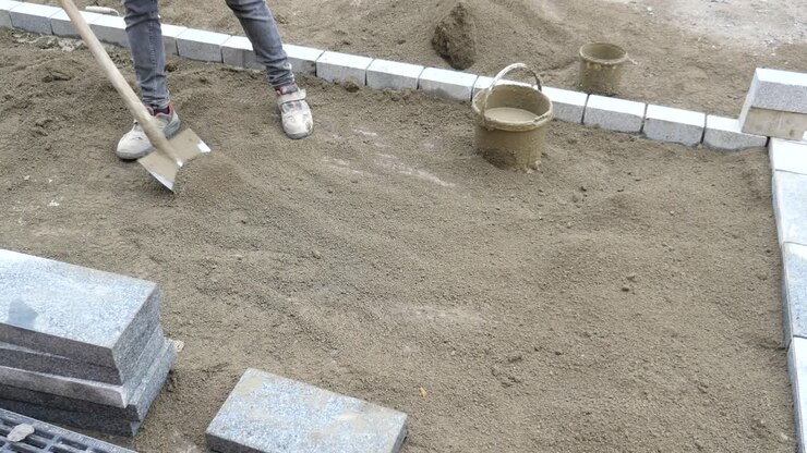 A construction worker lays bricks for a new driveway.