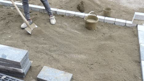 a construction worker lays bricks for a new driveway.