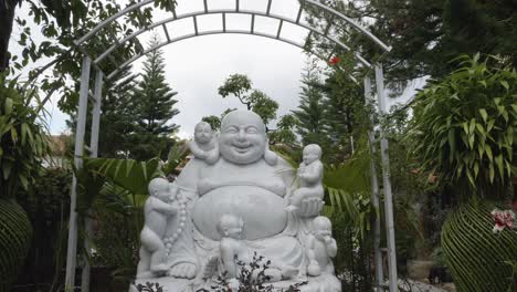 white marble sculpture of laughing buddha with five kids