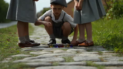 children playing marbles on a cobblestone path