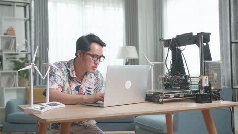 man working on a 3d printer and renewable energy models at home