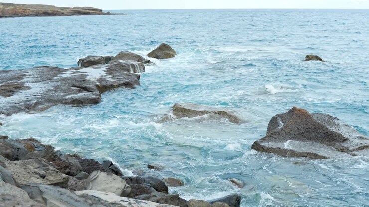 Vista di una costa rocciosa dolcemente lambita dalle onde dell'oceano, panoramica a sinistra