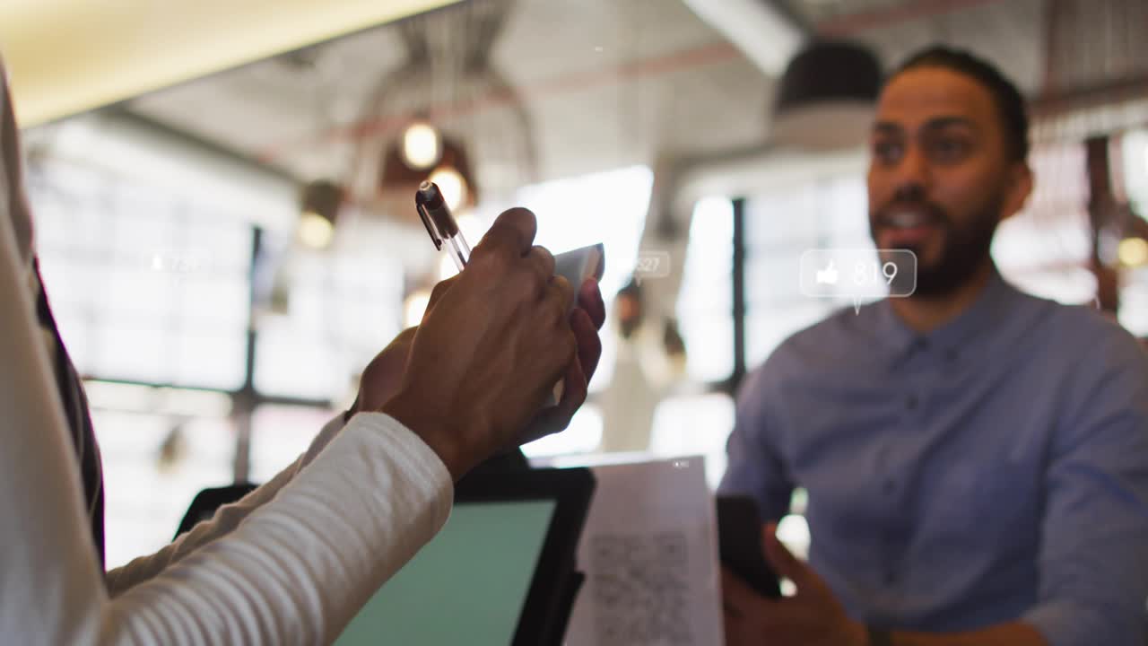 Woman writing notes as man gesturing, social media icons rising then dropping showing engagement