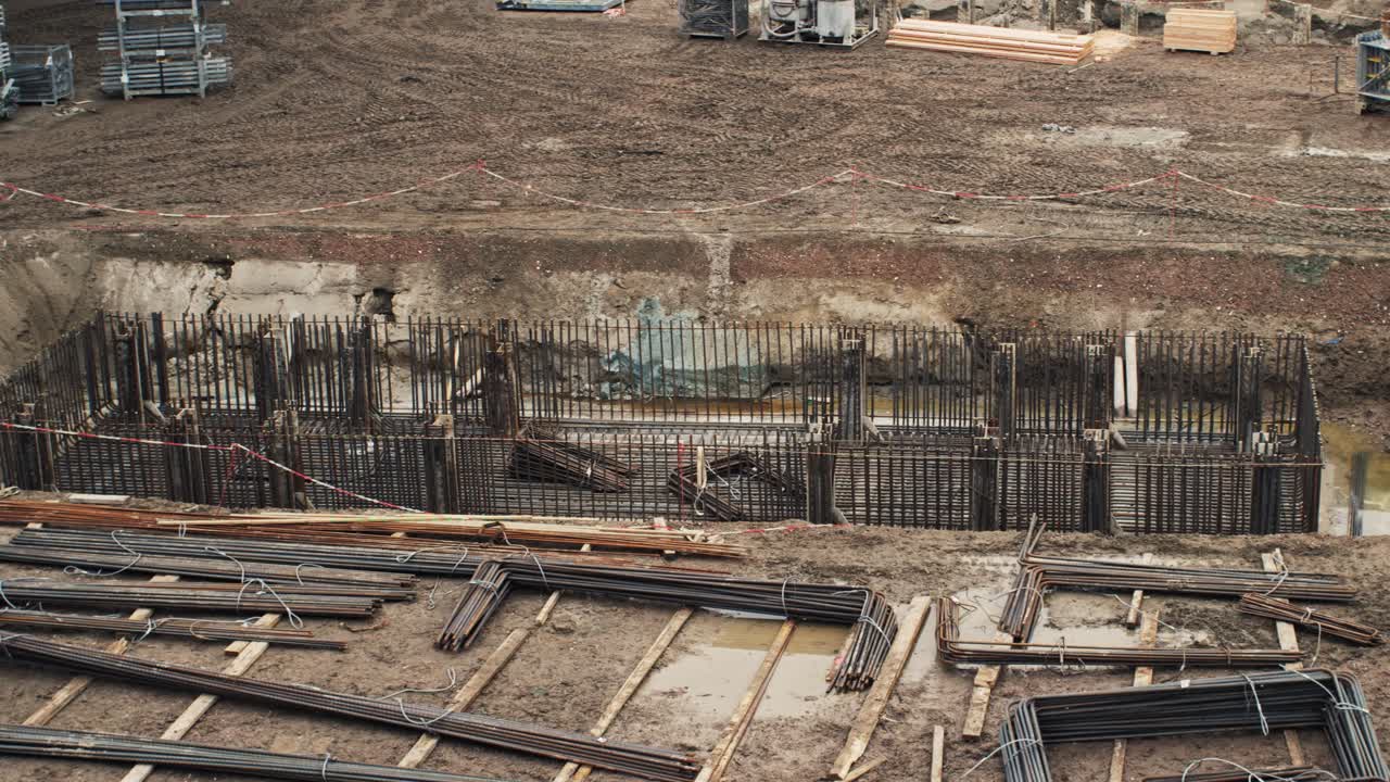 Pan shot of rebar framework for a column under construction at a flyover site with exposed earth and materials