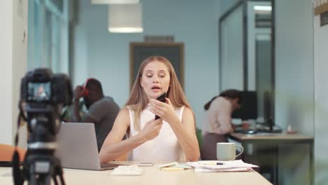 pretty woman recording video. female vlogger presenting difference of two phones