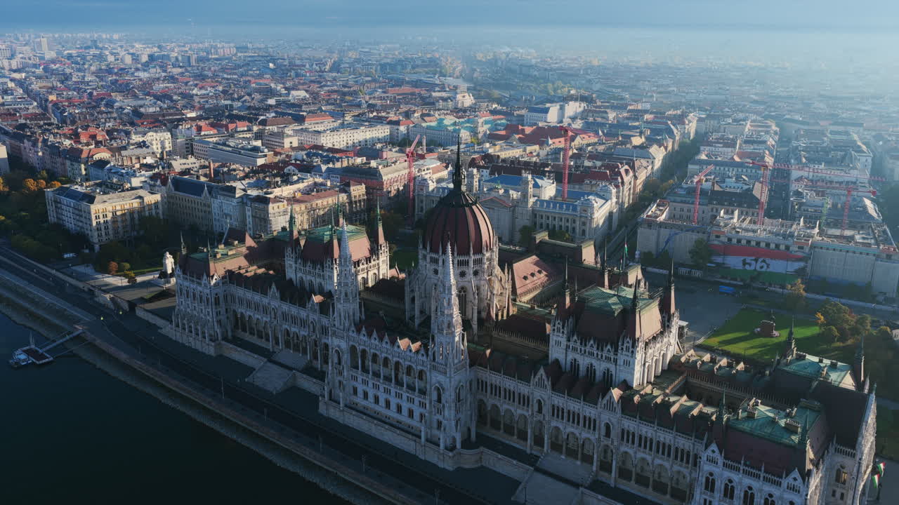 Morning light highlights the grand facade of the Hungarian Parliament stretching along the Danube’s reflective surface