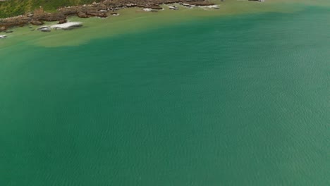 panning up aerial shot of a cliff wall along the coast in new zealand