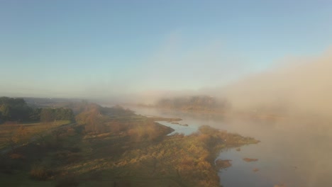 Drone-aerial-view-of-fog-over-the-Nemunas-river-during-sunrise-in-early-autumn-morning-in-Kaunas-county,-Lithuania