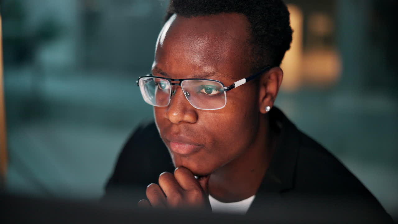 Focused African American man with glasses working in office