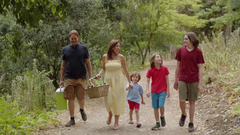 Front-view-of-happy-family-going-to-picnic-in-the-forest