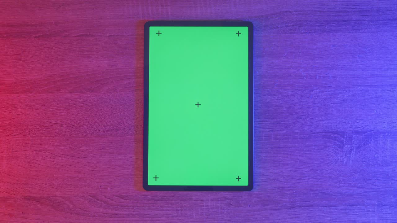 Bovenaanzicht van een laptopcomputer met een mock-up groen chromakey-scherm op een houten bureau, naast een notitieboekje met pennen, een bril en een glas water. Langzaam uitzoomen, close-up.