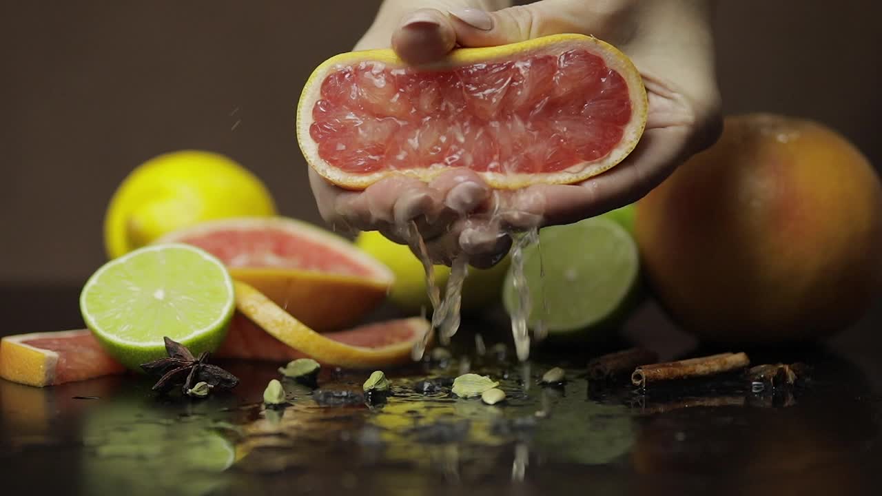 Kvinde presser en frisk og saftig grapefrugt med hænderne. Friske frugter
