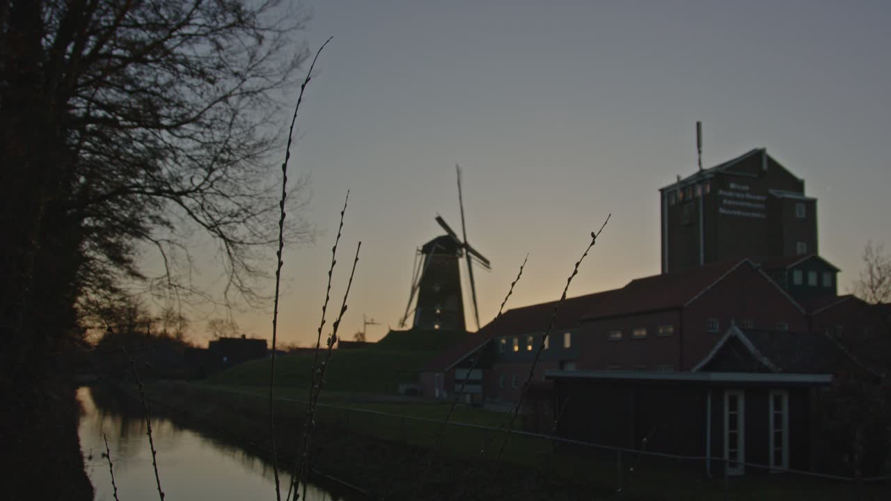 статичный вид на классическую ветряную мельницу в типичном голландском пейзаже на закате солнца