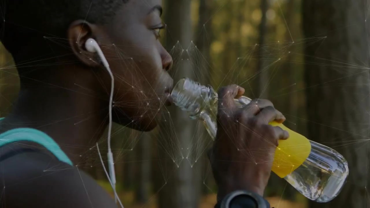 Fitnessløber skruer låget af og aktiverer digital globus, mens han/hun nipper til vand for hydrering på stien.