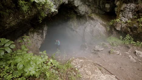 explorando la entrada de una cueva de niebla