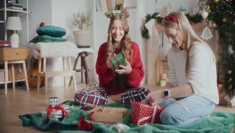 playful sisters wrapping christmas gifts at home