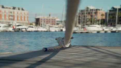 tracking shot passing under a docking line at a harbour with boatings in the background