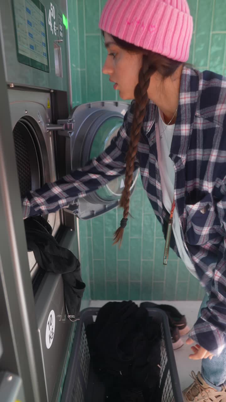 mujer lavando la ropa en una lavandería de autoservicio