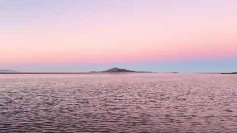 sunset over a calm sea with a distant island