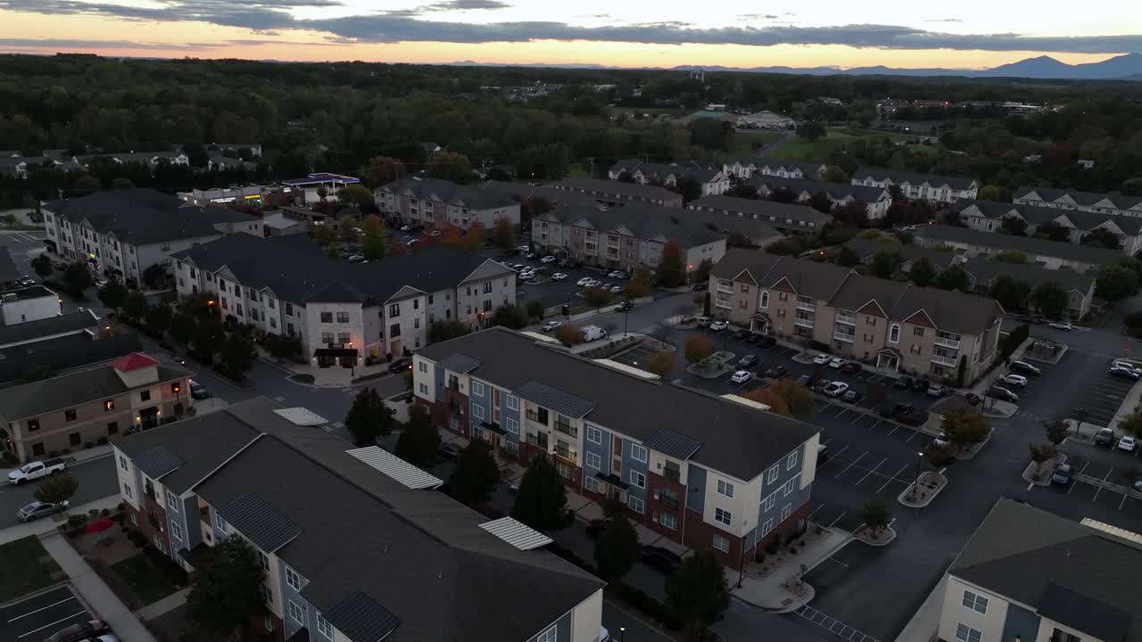 Dusk scene in American suburb town. Aerial view. Housing area and apartment buildings in autumn season. Colored facade of houses and homes. Wide shot