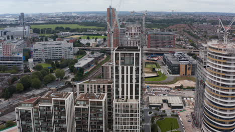 Backwards-reveal-of-modern-apartment-buildings-in-White-City.--Urban-neighbourhood-and-park-with-large-meadow-in-background.-London,-UK