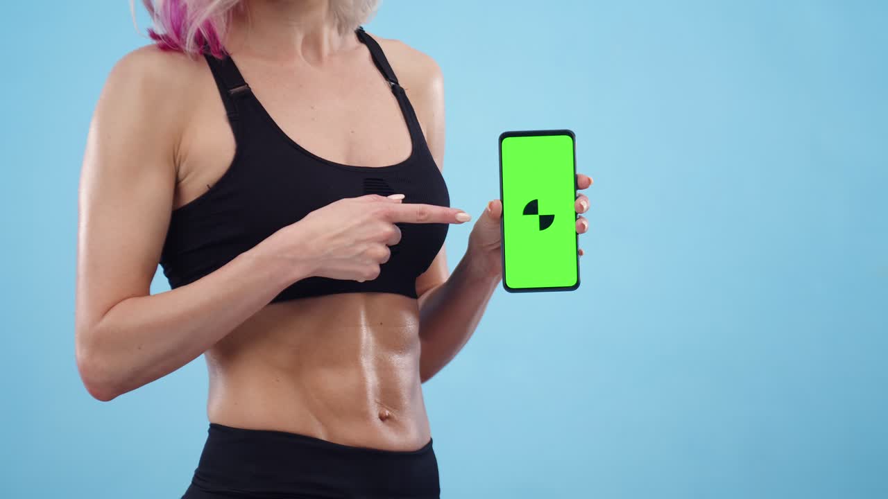 스포츠 여성은 푸른 배경에 손가락으로 초록색 화면을 가리키는 드폰을 들고, 언론의 클로즈업.