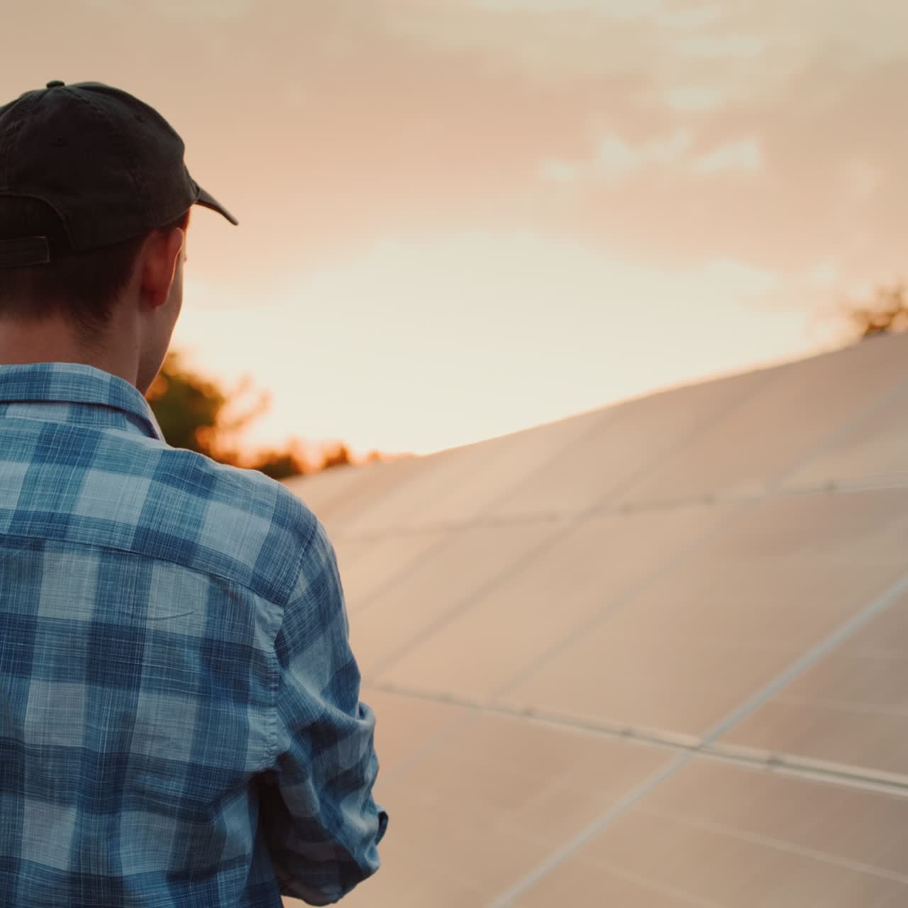 el orgulloso propietario de la planta de energía solar mira los paneles solares al atardecer