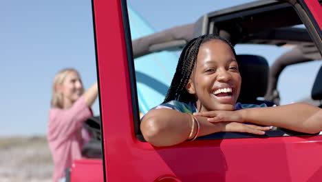 young african american woman leans on a car door on a road trip